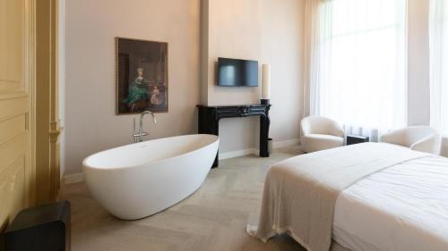 a white bath tub in a bedroom with a bed at Dam Residence - Boutique Hotel in Zaandam