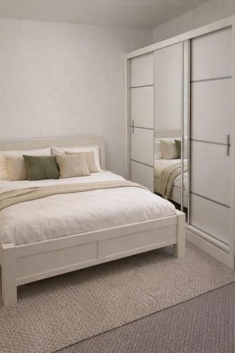 a white bedroom with a bed and a mirror at Apartmán Na Pavlači in Velký Třebešov