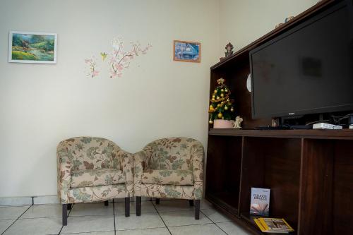 ein Wohnzimmer mit Sessel und Fernseher in der Unterkunft Casa Pet Friendly c 3 Quartos e Garagem no Jardim in Poços de Caldas