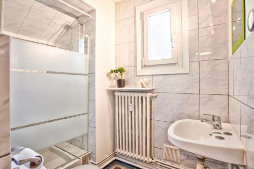 a white bathroom with a sink and a radiator at Le Chéron - Confort, Wi-Fi & commerces à deux pas in Caen