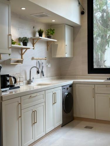 una cucina con mobili bianchi, un lavello e una lavastoviglie di شاليهات روز a Al Shafa