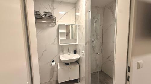 een witte badkamer met een wastafel en een douche bij Apart Schwalbennest in Imst