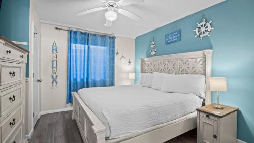 a bedroom with a white bed and blue walls at Romar Tower 1B in Orange Beach