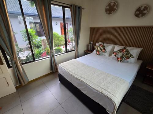 ein Schlafzimmer mit einem Bett in einem Zimmer mit Fenstern in der Unterkunft Bula Lodge Guest House in Nadi