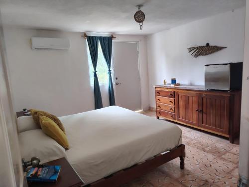 Schlafzimmer mit einem Bett, einem TV und einer Kommode in der Unterkunft Casa Nido Bacalar in Bacalar