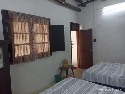 een slaapkamer met twee bedden, een tafel en een raam bij Casa Guacamaya in Izamal