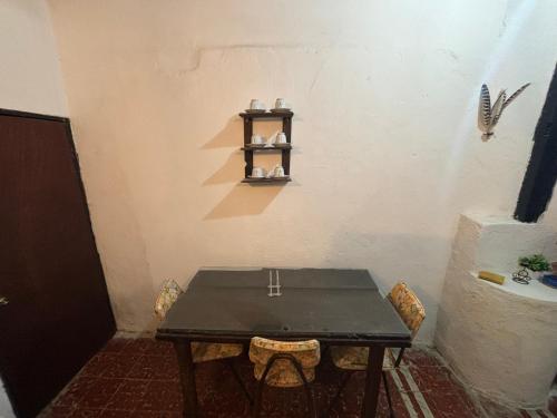 een tafel met twee stoelen en een plank aan de muur bij Casa Guacamaya in Izamal