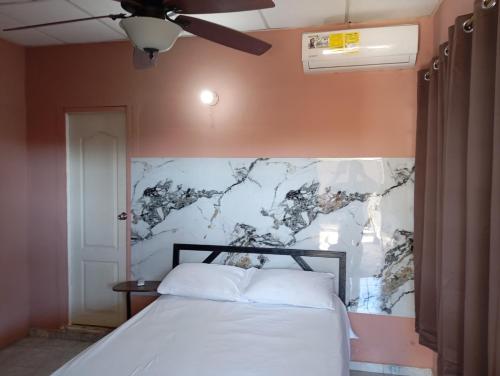 a bedroom with a white bed with a marble wall at Hostal familiar M&M los algarrobos in Los Algarrobos