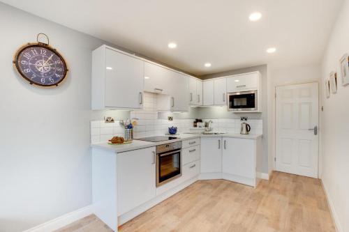 a kitchen with white cabinets and a clock on the wall at 1 Bed in Limeslade oc-hh387 in The Mumbles