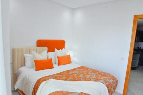 a bedroom with a bed with orange pillows and a mirror at Apartment in the center of Casablanca opposite the tram in Casablanca