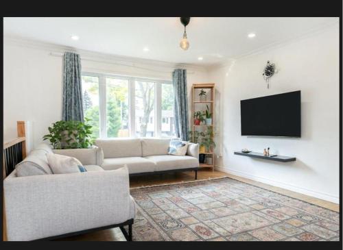 a living room with a couch and a flat screen tv at Beautiful First Floor in a House in Brossard
