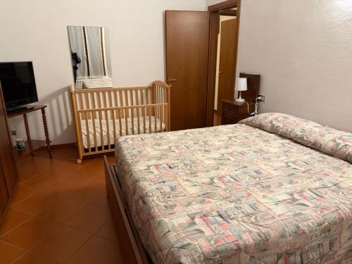 ein Schlafzimmer mit einem Bett, einem Kinderbett und einem TV in der Unterkunft Molinella Appartamento Amelia & Carlo in Molinella