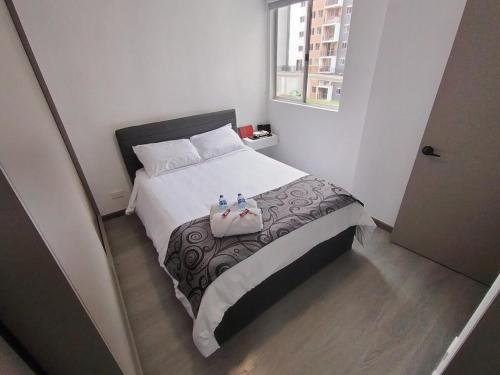 a small bedroom with a bed with white sheets and a window at Confortable Apartamento cerca Aerop JMC in Rionegro