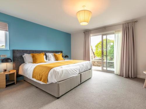 a bedroom with blue walls and a bed with yellow pillows at 3 Bed in Saltash oc-87717 in St. Mellion