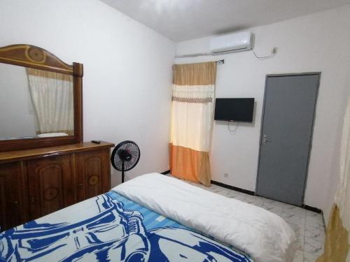 a bedroom with a bed and a mirror and a window at Résidence hibis chez M&B in Saly Portudal