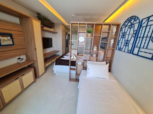 een woonkamer met een bed en een kamer met een televisie bij Beach Class Summer in Porto De Galinhas