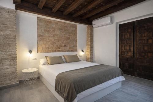 El Torreón 1870 في غرناطة: غرفة نوم بها سرير وجدار من الطوب