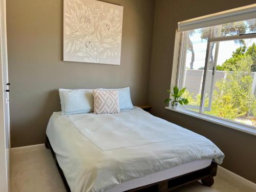 een klein bed in een kamer met een raam bij Kommetjie Mountain Oasis in Kommetjie