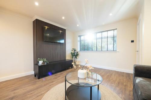 een woonkamer met een bank en een tv aan de muur bij Calgary Residence in Mellor