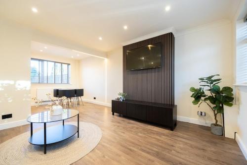 a living room with a table and a tv on a wall at Calgary Residence in Mellor