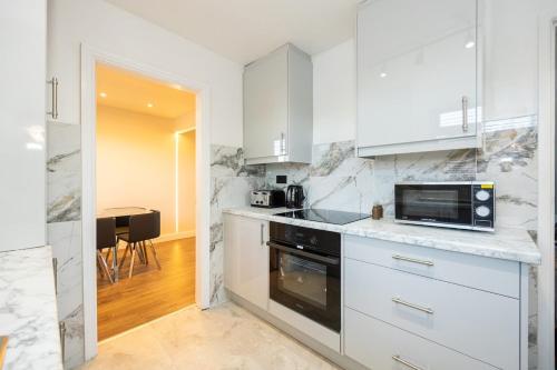a kitchen with white cabinets and a microwave at Calgary Residence in Mellor