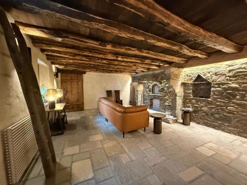 a living room with a couch and a stone wall at Mansio 1695 Chambres d'hôtes in Pont-Saint-Martin