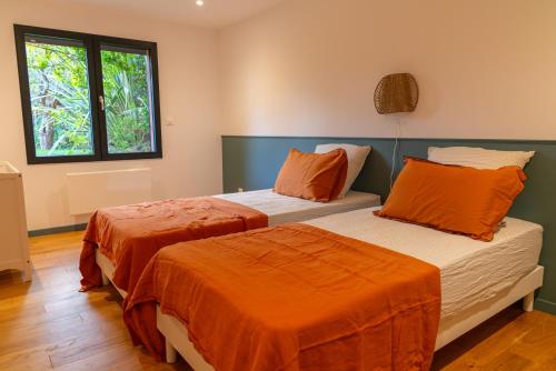 2 Betten mit orangefarbener Bettwäsche in einem Zimmer in der Unterkunft Villa Les Restanques in Aix-en-Provence
