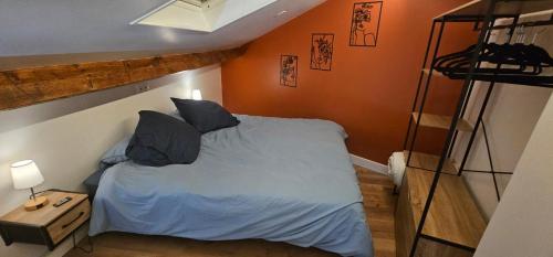 een slaapkamer met een bed met blauwe lakens en kussens bij Cozy Loft sous les toits in Le Kremlin-Bicêtre
