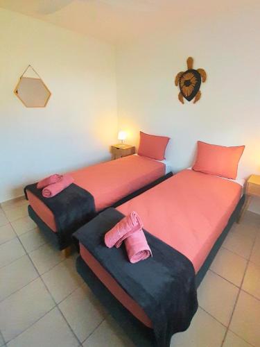 two beds in a room with pink sheets at La Case Auvergnate in Anse-Bertrand