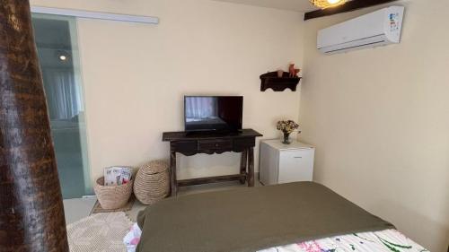 una camera con letto e TV su un tavolo di Suite completa com área verde a Camaçari