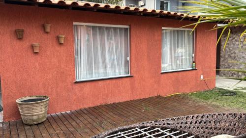 una casa rossa con due finestre e un secchio di Suite completa com área verde a Camaçari
