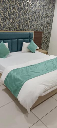 a large bed with a blue headboard and pillows at Hotel Nest View In in Ahmedabad