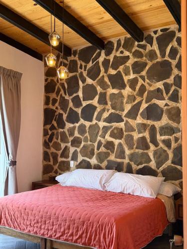 a bedroom with a stone wall with a bed at Cábaña bonita vista in Atemajac de Brizuela