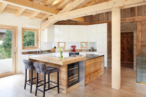 une cuisine avec des plafonds en bois et un grand îlot avec des tabourets de bar dans l'établissement Marmotte Mountain Eco Lodge, à Chamonix-Mont-Blanc