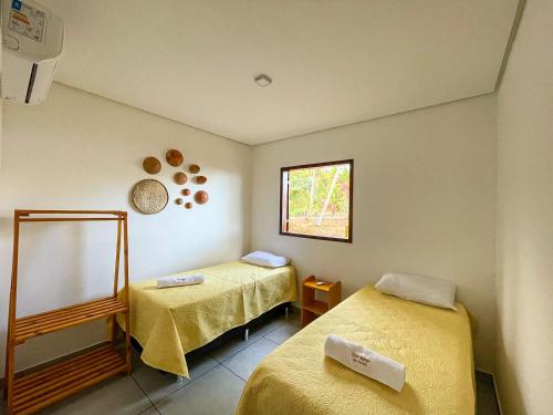 una stanza con due letti e una finestra di Chalé Refúgio dos Corais 1 a Japaratinga