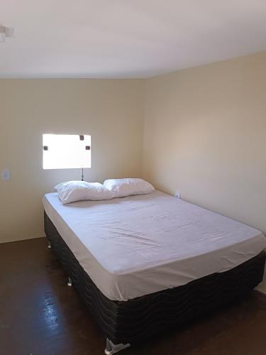 a bedroom with a bed with white sheets and a light at Loft confortável in Morro do Chapéu