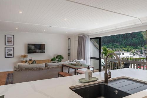 eine Küche mit einem Waschbecken und ein Wohnzimmer mit einem Sofa in der Unterkunft Central City Queenstown Retreat - 3 Bedroom Apartment in Queenstown