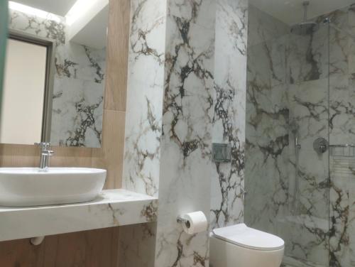 a bathroom with a sink and a toilet and a mirror at Thassos Hotel in Pefkari