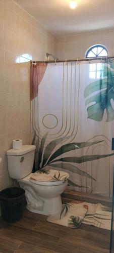 a bathroom with a toilet and a shower curtain at Hotel y Cabañas El Taxho in El Porvenir