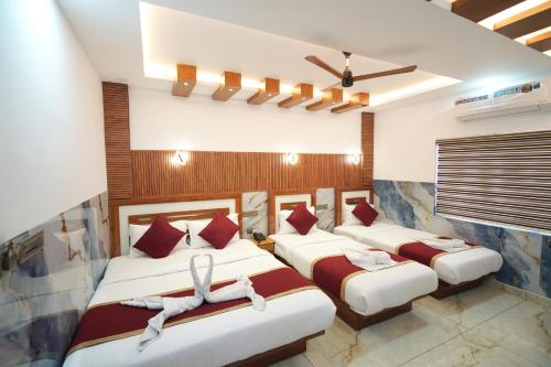 Habitación con 3 camas con almohadas rojas en MARINA SUITES AIRPORT HOTEL, en Kochi