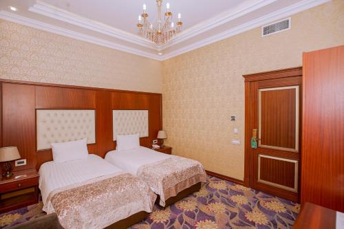 una camera da letto con due letti e un lampadario di Clover Hotel a Baku