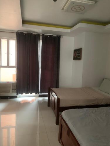 a bedroom with two beds and a window at Birch tower Condominium in Manila
