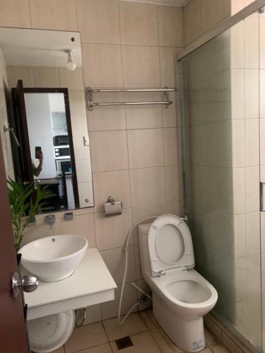 a bathroom with a sink and a toilet and a mirror at Birch tower Condominium in Manila