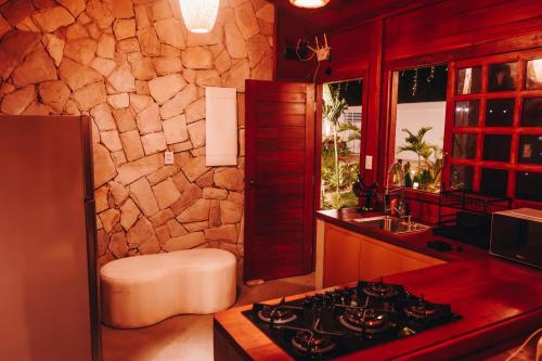 a kitchen with a stove and a stone wall at Lagoon Paradise in Fortim