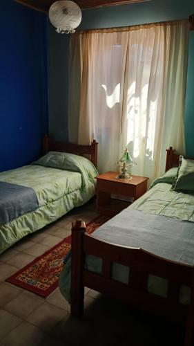 una camera da letto con due letti e una finestra di Alojamiento en Malargue a Malargüe