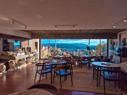a restaurant with tables and chairs and a large window at Barrieiro - Art & Nature in Marvão
