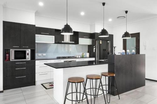 a kitchen with black and white cabinets and bar stools at Two Williams Estate - Hunter Valley in Cessnock