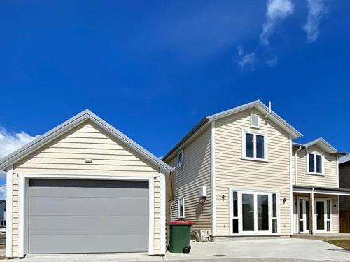 a house with a white garage door in a driveway at Standalone Home Near Bruce Pulman Park 5BR 3 Baths in Auckland
