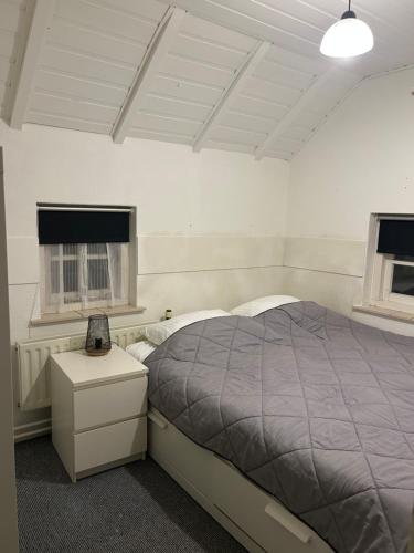 a bedroom with a bed and a table and two windows at Huize Kroezzz sfeervolle authentieke vakantie woning met 3 slaapkamers, omheinde tuin en honden welkom in Goor