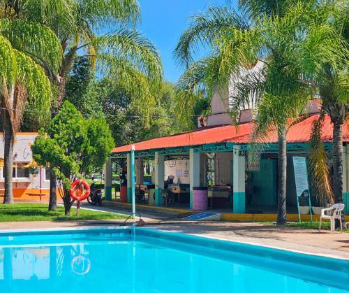 a pool in front of a building with palm trees at Parque Girasoles Balneario & Cabañas in San Francisco del Rincón